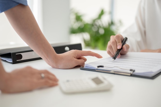 Uma empresária apontando o dedo para um relatório enquanto discute o trabalho com sua equipe