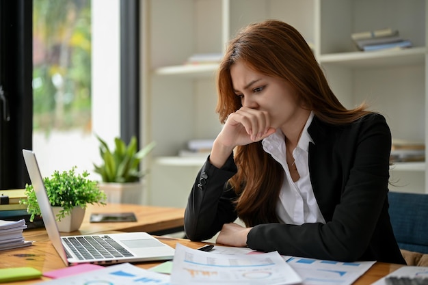 Uma empresária asiática pensativa e estressada se concentra em relatórios de dados financeiros de negócios