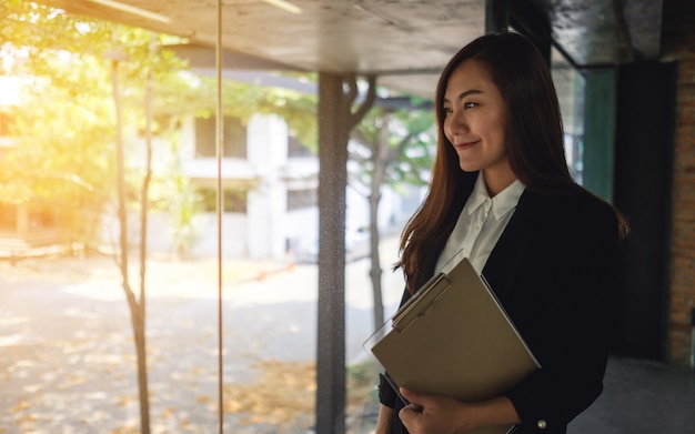 Uma empresária bem-sucedida asiática em pé no escritório