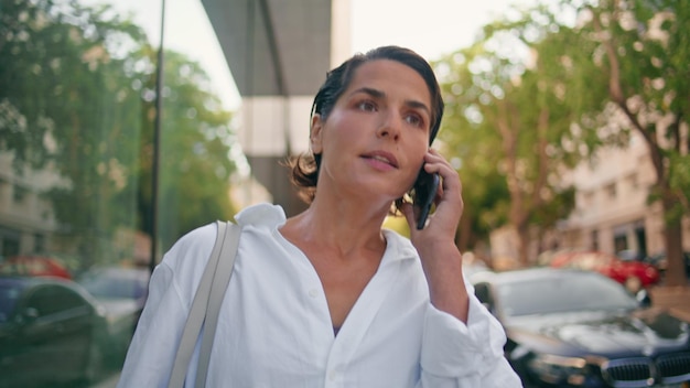 Uma empresária confiante ligando para um smartphone indo para uma senhora de rua falando