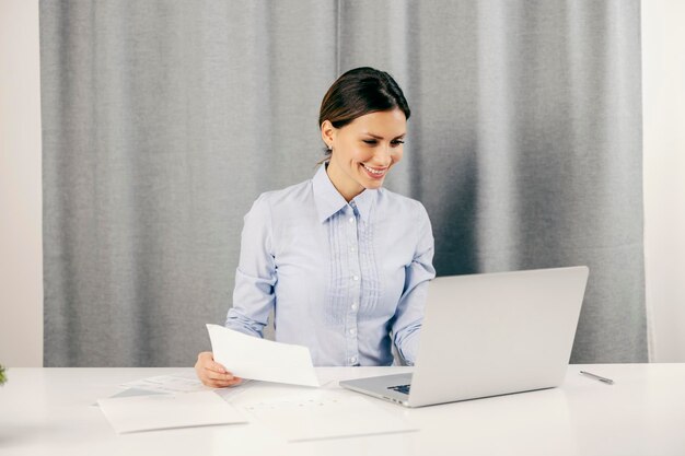 Uma empresária feliz trabalhando no laptop em casa