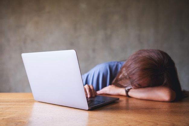 Uma empresária ou um estudante se cansa e dorme na mesa enquanto trabalha no laptop em casa