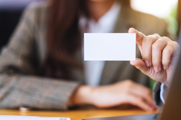 Uma empresária segurando e mostrando cartões de visita em branco no escritório