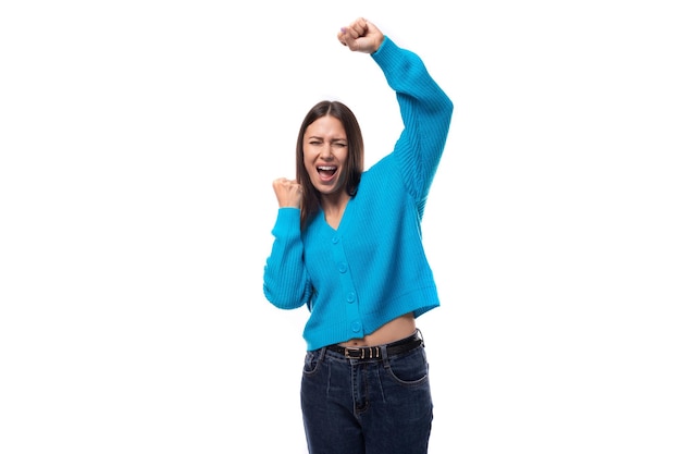 Uma encantadora mulher caucasiana de cabelo preto vestida com um cardigan azul está dançando.