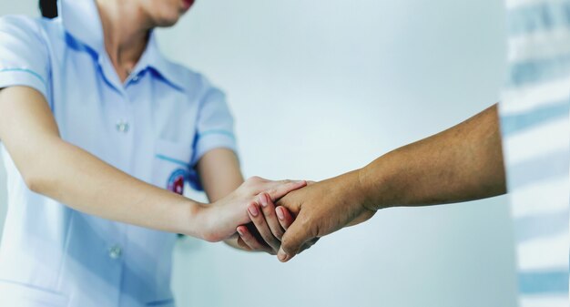 Uma enfermeira apertando as mãos para encorajar o paciente