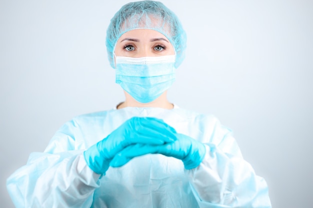 Uma enfermeira com uma bata médica e máscara cruzou as mãos na frente dela