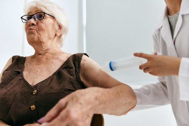Uma enfermeira dando uma injeção em uma mulher idosa com um passaporte de vacina com seringa