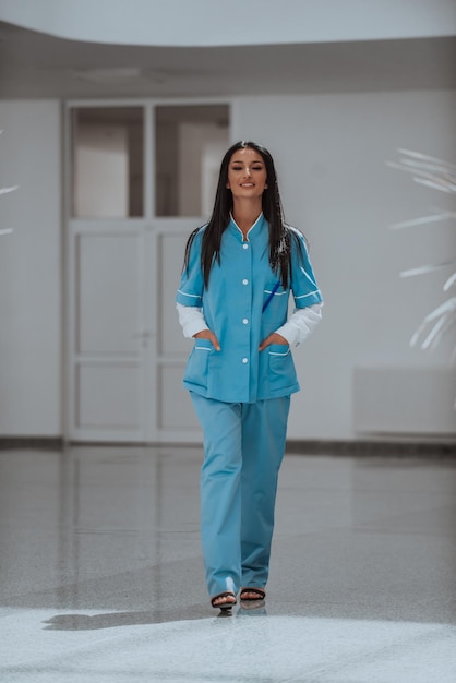 Uma enfermeira de uniforme azul parada no corredor de um hospital moderno