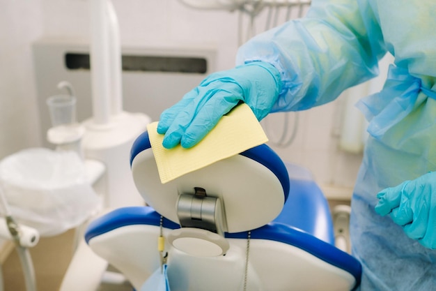 Uma enfermeira desinfeta as superfícies de trabalho no consultório do dentista