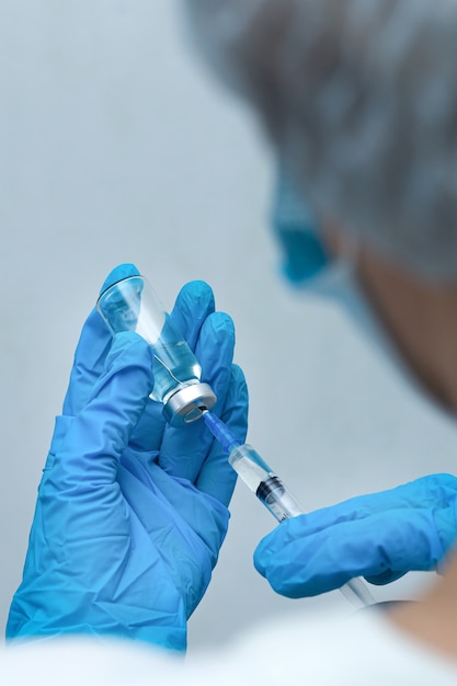 Uma enfermeira disca a injeção na seringa, vacinação
