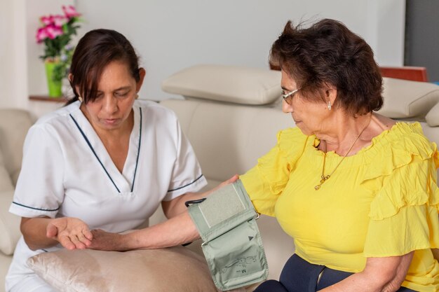 Uma enfermeira explica a uma idosa como usar um monitor digital de pressão arterial