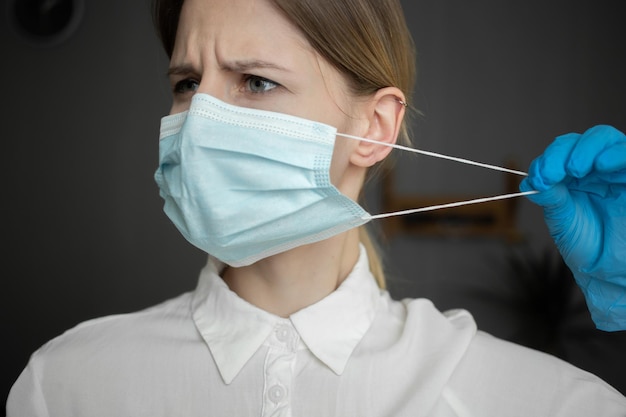 Uma enfermeira usando luvas de proteção remove a máscara