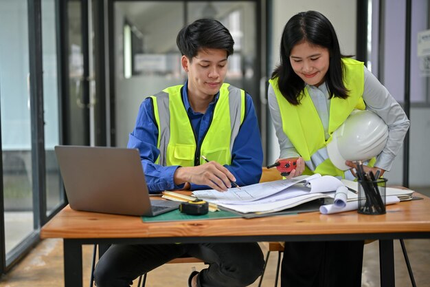 Uma engenheira de construção asiática profissional está trabalhando com seu colega no escritório