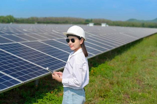 Uma engenheira usando capacete na Fazenda de Células Fotovoltaicas ou Eco Campo de Painéis Solares