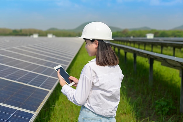 Uma engenheira usando capacete na Fazenda de Células Fotovoltaicas ou Eco Campo de Painéis Solares