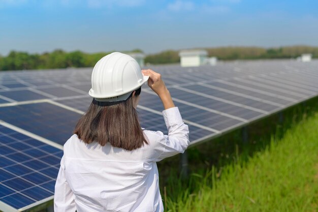 Uma engenheira usando capacete na fazenda de células fotovoltaicas ou no campo de painéis solares