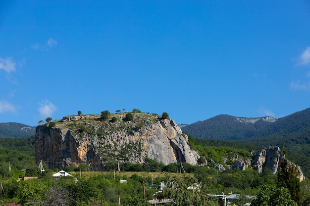 Uma enorme rocha calcária vermelha, red stone, com montanhas ao fundo.