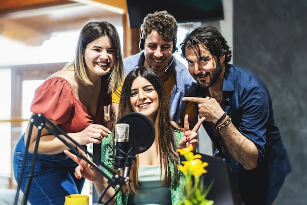 Uma equipe de quatro apresentadores cumprimenta o público de seu podcast de vlog de transmissão ao vivo pela Internet, um grupo de influenciadores fala ao microfone durante uma transmissão ao vivo