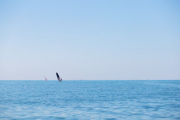 Uma equipe de surfistas flutua no mar praticando windsurf