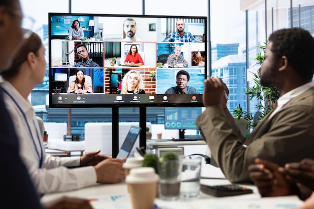 Uma equipe diversificada de trabalhadores analisa as atualizações do projeto com os acionistas em videoconferência