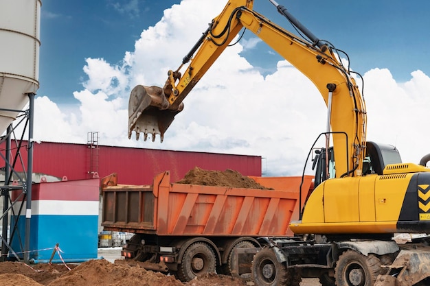 Uma escavadeira carrega solo ou areia em um caminhão basculante Desenvolvimento de poços Terraplanagem com a ajuda de equipamentos de construção pesados