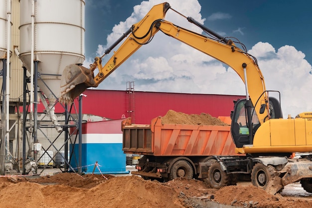 Uma escavadeira carrega solo ou areia em um caminhão basculante Desenvolvimento de poços Terraplanagem com a ajuda de equipamentos de construção pesados