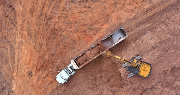 Uma escavadeira está carregando terra em um caminhão basculante que é equipamento de construção pesada