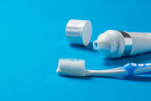 Uma escova de dentes com cerdas de silicone e um tubo de pasta de dentes em um fundo azul. Significa cuidar da cavidade oral.