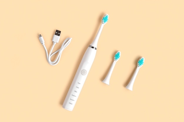 Uma escova de dentes elétrica branca com uma escova de dentes em um fundo de pêssego.