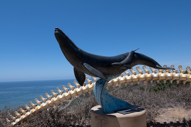 Uma escultura em tamanho real de uma baleia ao lado da espinha de uma baleia no oceano