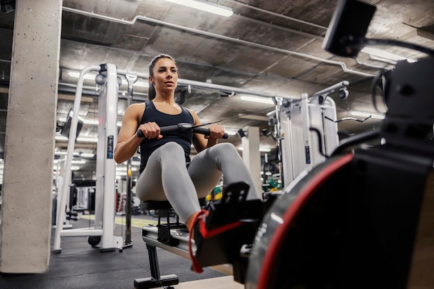 Uma esportista em forma está se exercitando com uma máquina de remo em uma academia