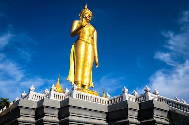 Uma estátua dourada de buddha no altar para a adoração em um fundo bonito do céu azul.