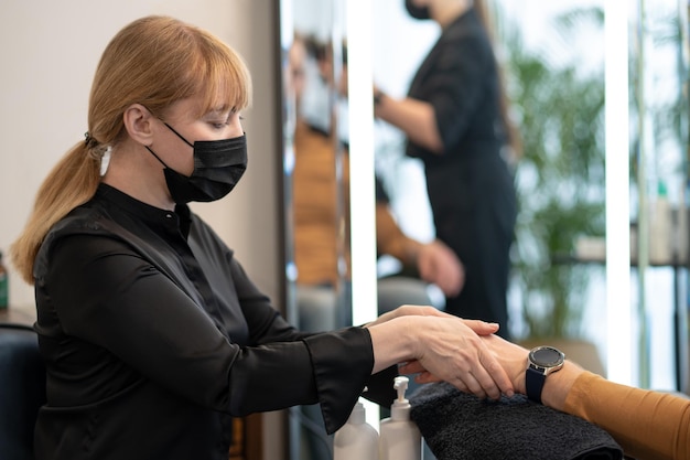 Uma esteticista fazendo massagem de mãos para o cliente masculino