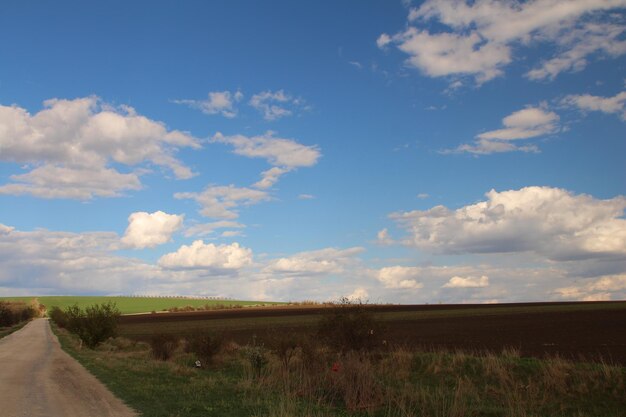 uma estrada com um carro a descer e um céu com nuvens