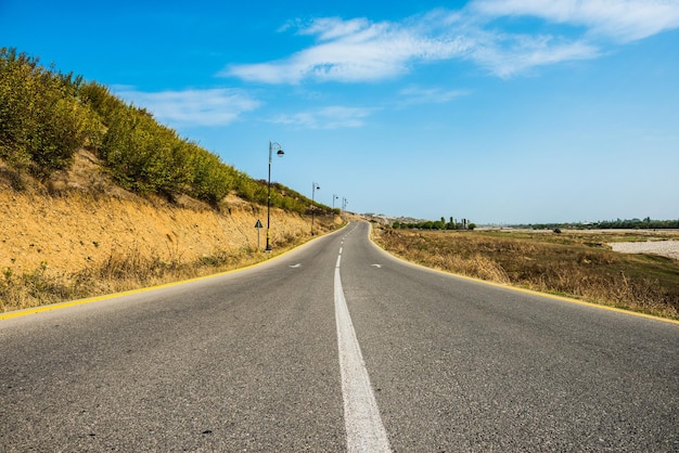 Uma estrada com um céu azul e uma faixa branca que diz 'estrada para a direita'