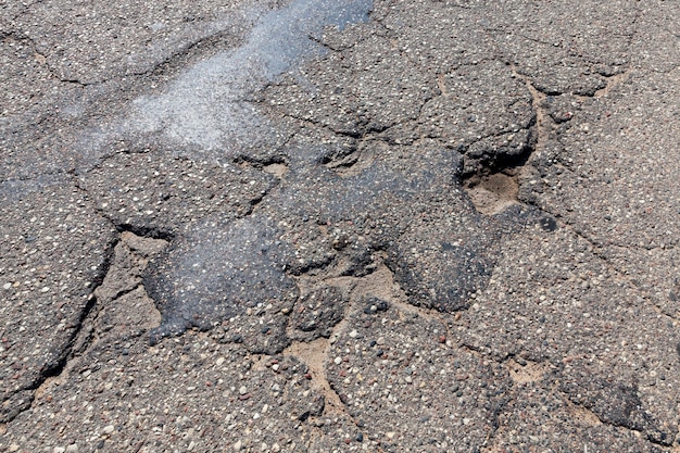 Uma estrada de asfalto com muitos buracos e estragos