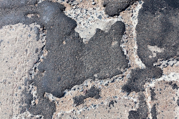 Uma estrada de asfalto ruim que foi reparada muitas vezes