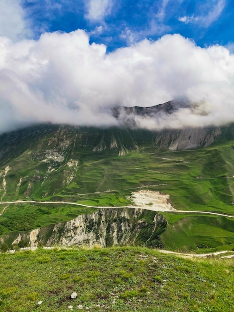 Uma estrada nas montanhas do Daguestão com grandes montanhas ao fundo e nuvens Rússia