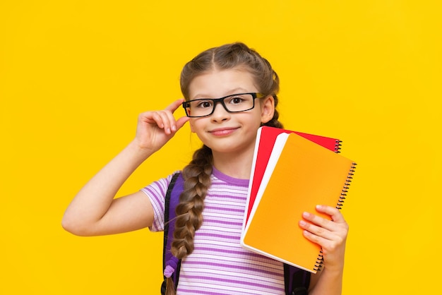 Uma estudante bonita em uma camiseta listrada segura cadernos na mão