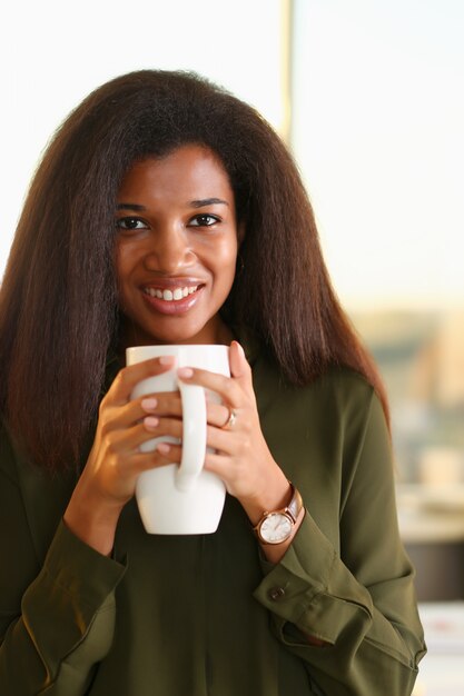 Uma estudante de mulher negra em um escritório segura uma xícara de chá