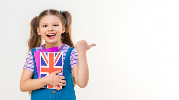 Uma estudante segura um livro de inglês nas mãos e aponta o dedo para o lado do anúncio.