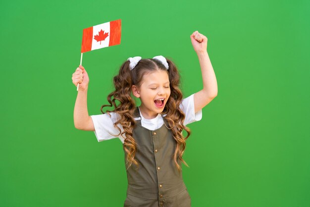 Uma estudante segura uma bandeira canadense e se alegra. kid está muito animado em estudar no exterior.