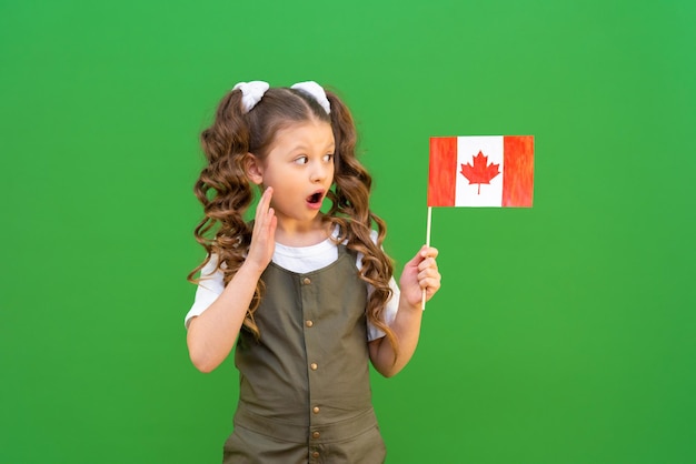 Uma estudante segura uma bandeira canadense e sorri Estudando em uma escola canadense e recebendo educação