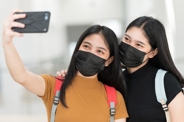 Uma estudante universitária com um telefone tirando uma selfie na universidade, de volta às aulas,