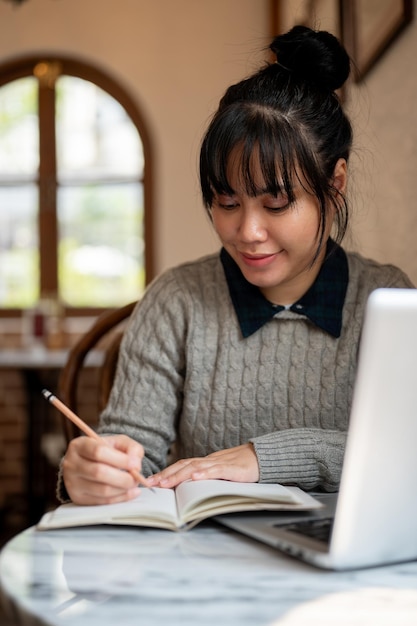 Uma estudante universitária em roupas casuais está lendo um livro ou fazendo lição de casa em um café