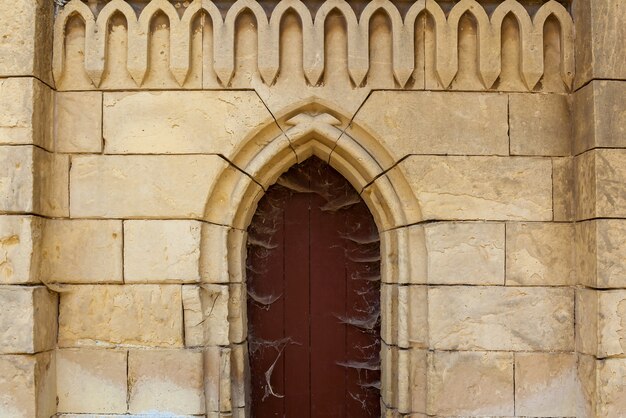 Uma fachada de tijolos antigos com uma porta de igreja de madeira e decorações estampadas.
