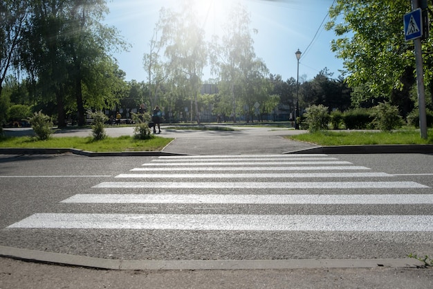 Uma faixa de pedestres para pedestres atravessando a faixa de pedestres vazia da rua para o parque