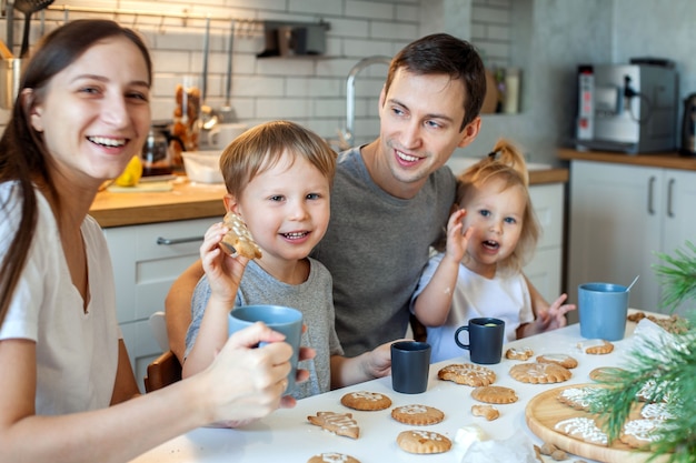 Uma família alegre decora o natal com biscoitos de gengibre e se diverte na cozinha de casa cheia de estilo