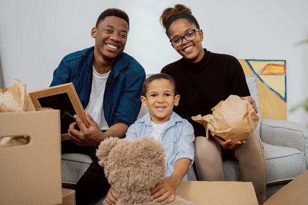 Uma família amorosa se senta no sofá da sala de estar e desempacota as caixas depois de se mudar para um novo apartamento