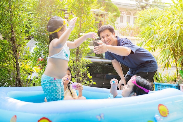 Uma família asiática está brincando em uma piscina inflável se divertindo jogando soprando